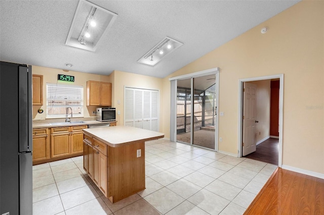 kitchen with a center island, light countertops, lofted ceiling, appliances with stainless steel finishes, and a textured ceiling