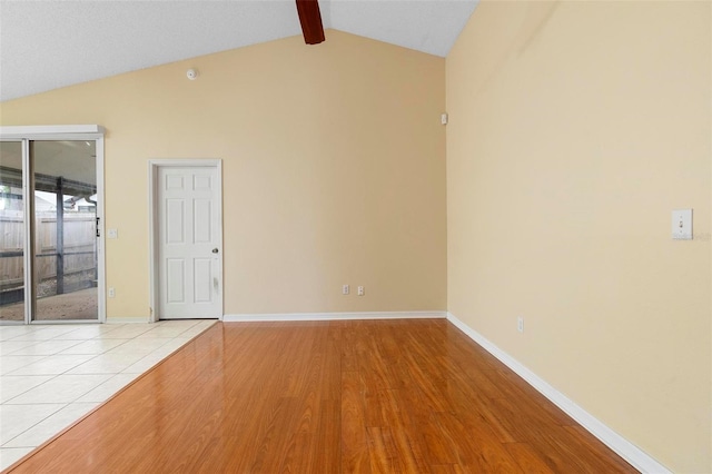 spare room with light wood-style flooring, vaulted ceiling with beams, and baseboards