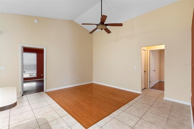 spare room with light tile patterned floors, high vaulted ceiling, and baseboards