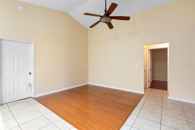 spare room featuring light tile patterned flooring, baseboards, lofted ceiling, and a ceiling fan