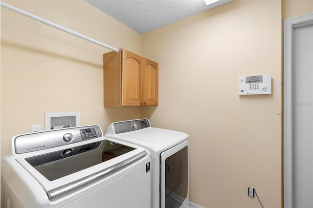 laundry area with cabinet space, a textured ceiling, and washing machine and clothes dryer