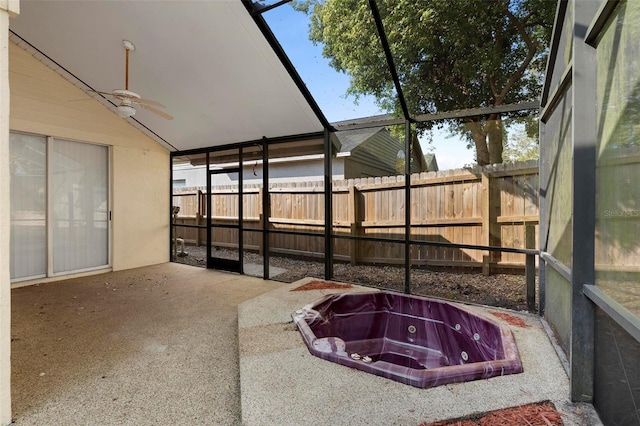 unfurnished sunroom featuring lofted ceiling, a hot tub, and ceiling fan