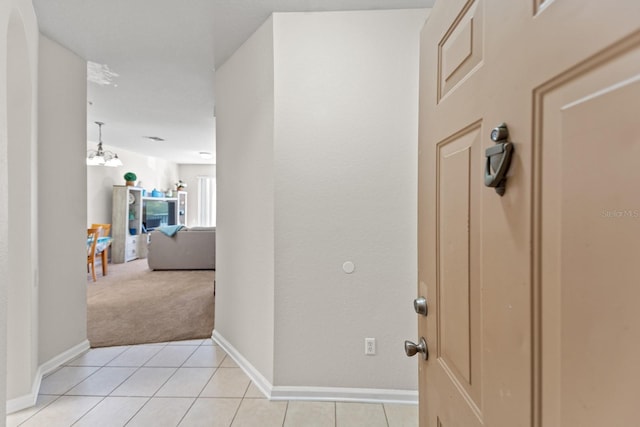hall with baseboards, light carpet, and light tile patterned flooring