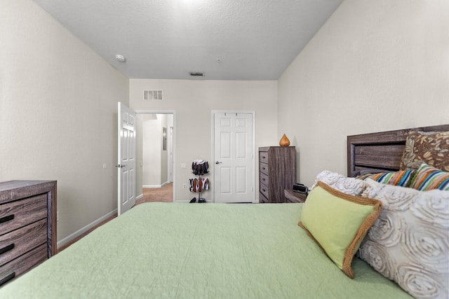 bedroom with baseboards, visible vents, carpet floors, and a textured ceiling