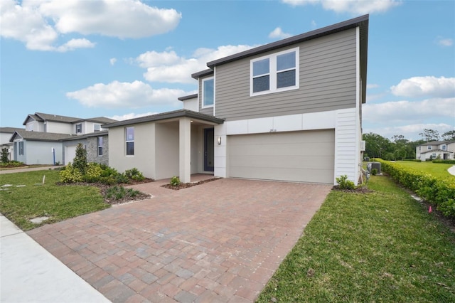 view of front of property featuring a garage, a front yard, stucco siding, and decorative driveway