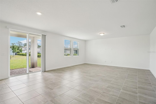 spare room featuring plenty of natural light, visible vents, and baseboards