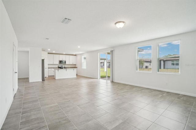 unfurnished living room featuring recessed lighting, baseboards, and a healthy amount of sunlight