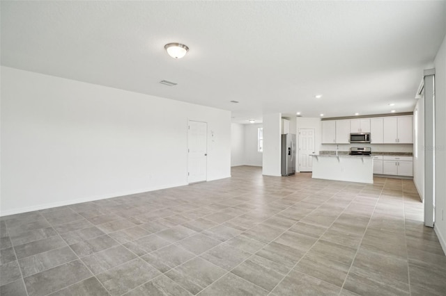 unfurnished living room with recessed lighting, visible vents, and baseboards
