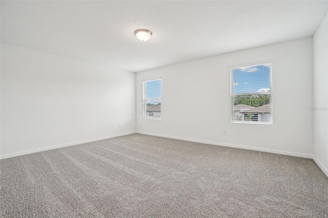 spare room featuring baseboards and carpet floors