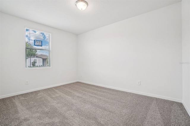 carpeted spare room featuring baseboards