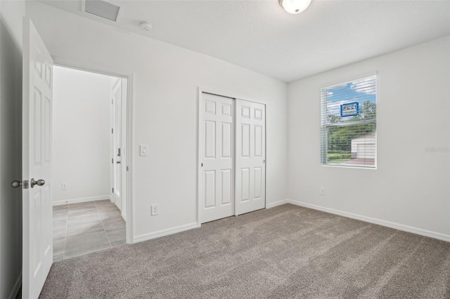 unfurnished bedroom with visible vents, a closet, baseboards, and carpet floors