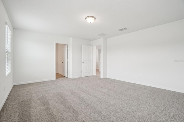 spare room featuring visible vents, baseboards, and carpet