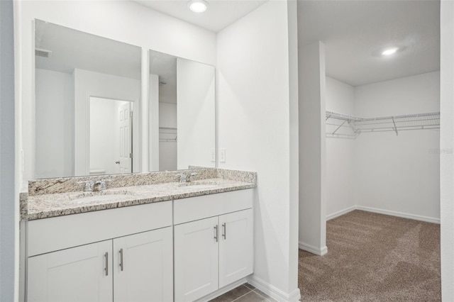 full bath with double vanity, a sink, a spacious closet, and visible vents
