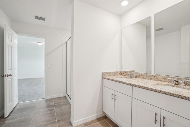 full bathroom featuring a shower stall, double vanity, a sink, and visible vents
