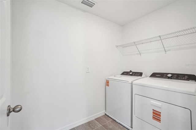 clothes washing area with visible vents, baseboards, tile patterned floors, laundry area, and washer and clothes dryer