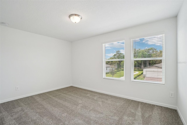 carpeted empty room featuring baseboards