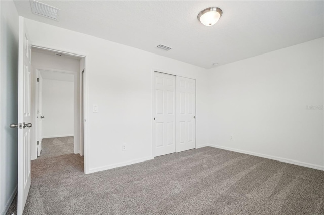 unfurnished bedroom with visible vents, baseboards, a closet, and carpet