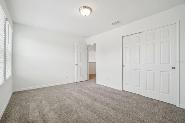 unfurnished bedroom with a closet, carpet flooring, baseboards, and visible vents