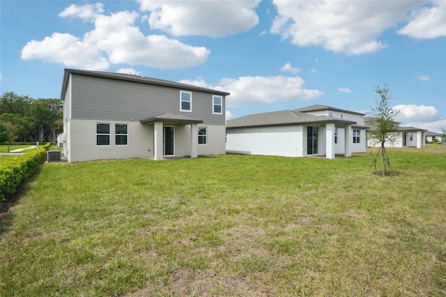 back of house featuring central AC, stucco siding, and a lawn