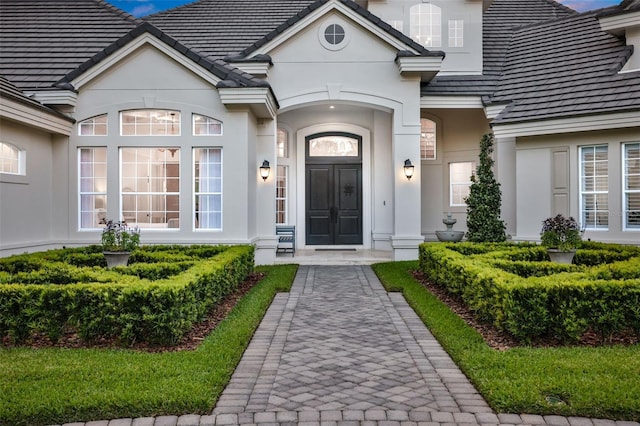 entrance to property with stucco siding and a tile roof