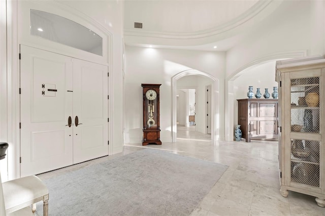 entryway with arched walkways, visible vents, marble finish floor, and a high ceiling