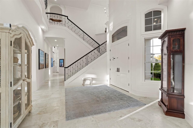 foyer entrance featuring stairway, baseboards, and a high ceiling