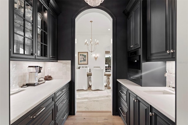 kitchen with a notable chandelier, dark cabinetry, light countertops, and a sink