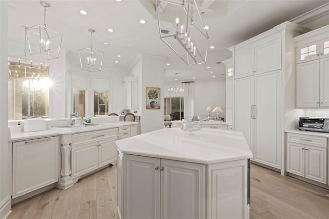 kitchen with recessed lighting, a sink, white cabinets, a notable chandelier, and a center island