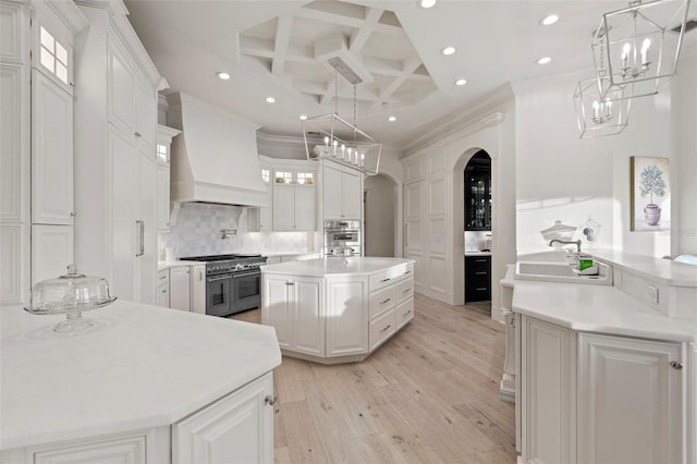 kitchen featuring a sink, double oven range, coffered ceiling, arched walkways, and custom exhaust hood