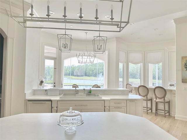 kitchen featuring dishwasher, crown molding, light countertops, and a sink