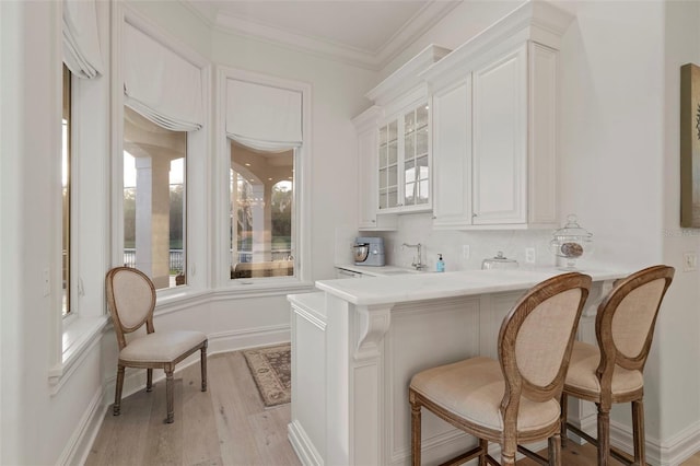 bar with light wood-style flooring, baseboards, backsplash, and ornamental molding