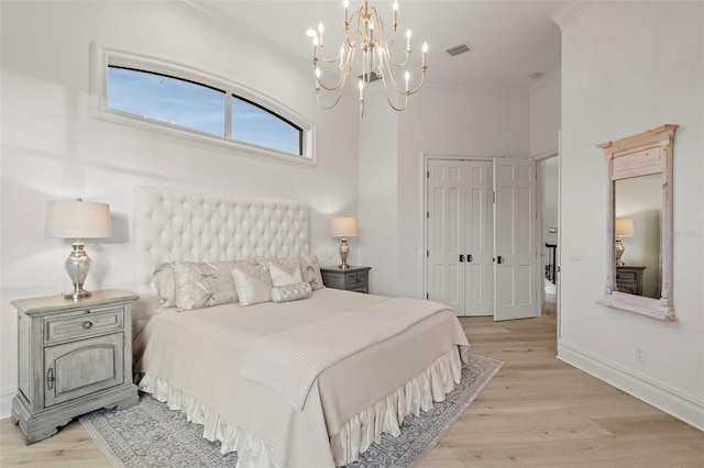 bedroom with baseboards, light wood finished floors, ornamental molding, a closet, and a notable chandelier