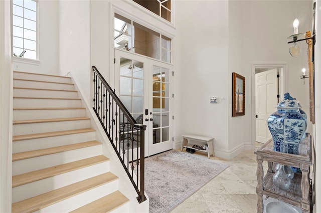 entrance foyer featuring stairway, french doors, baseboards, and a towering ceiling