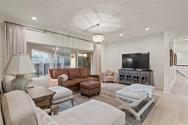 living area with wood finished floors, baseboards, recessed lighting, arched walkways, and ornamental molding