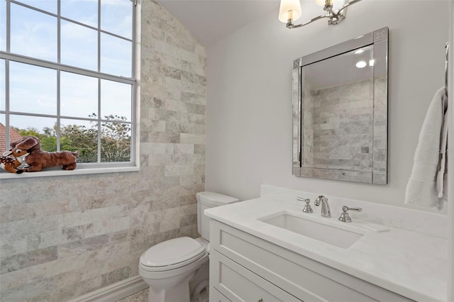 bathroom with lofted ceiling, toilet, an inviting chandelier, and vanity