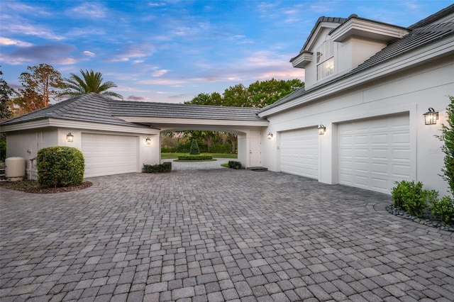 garage at dusk featuring decorative driveway