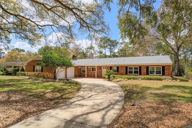 ranch-style house featuring a front lawn, concrete driveway, an attached garage, brick siding, and a chimney