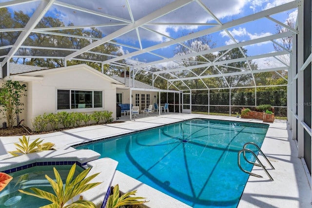 pool featuring glass enclosure, a patio, and an in ground hot tub