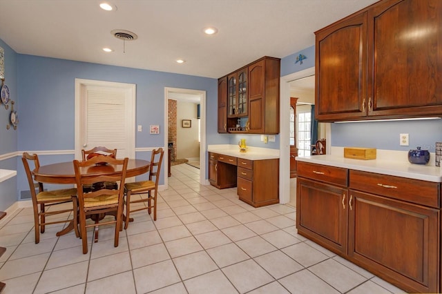 kitchen with light tile patterned floors, visible vents, built in desk, and light countertops