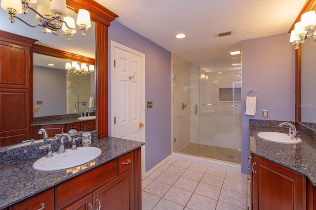 bathroom featuring an inviting chandelier, a shower stall, tile patterned floors, and a sink