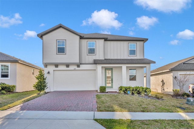 view of front of house featuring a front lawn, decorative driveway, an attached garage, and roof with shingles