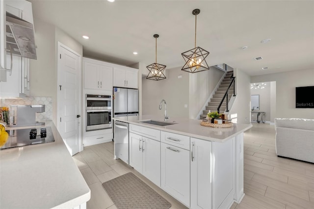 kitchen with open floor plan, decorative backsplash, appliances with stainless steel finishes, white cabinets, and a sink