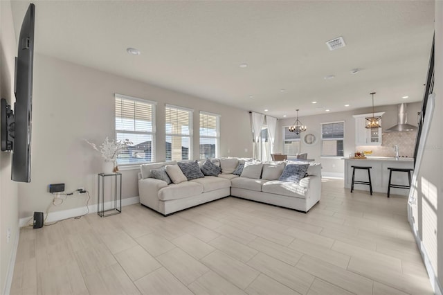 living area with an inviting chandelier, recessed lighting, baseboards, and visible vents