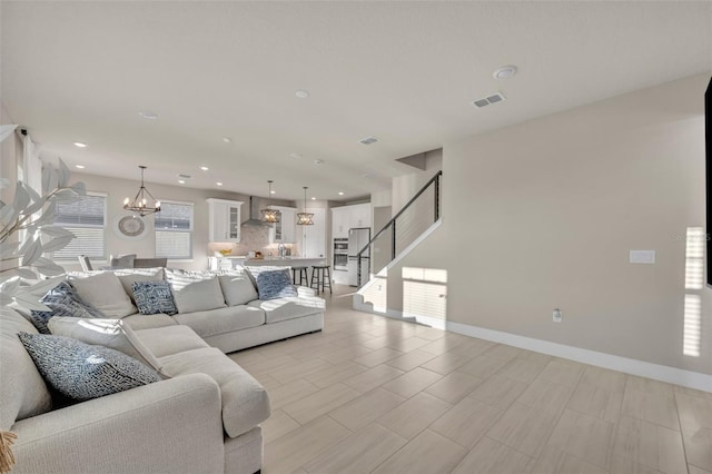 living room featuring visible vents, baseboards, stairway, recessed lighting, and a notable chandelier