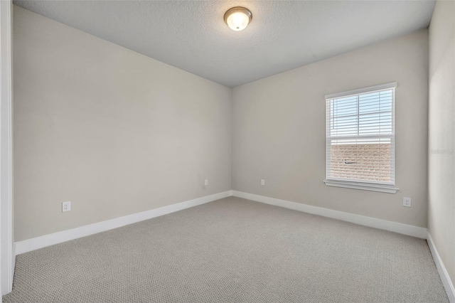 carpeted empty room featuring a textured ceiling and baseboards