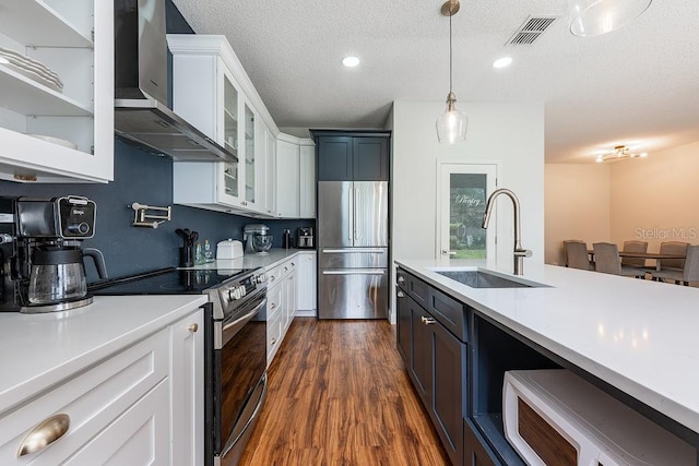 kitchen featuring visible vents, a sink, light countertops, appliances with stainless steel finishes, and wall chimney exhaust hood