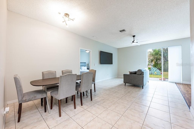 dining room with light tile patterned flooring, a ceiling fan, visible vents, and a textured ceiling