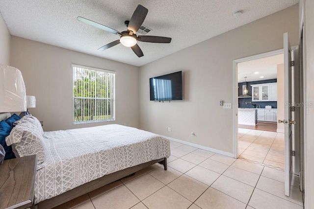 bedroom with light tile patterned floors, visible vents, baseboards, ceiling fan, and a textured ceiling