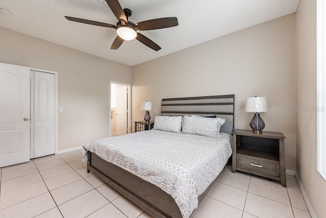 bedroom with light tile patterned flooring, a textured ceiling, and baseboards