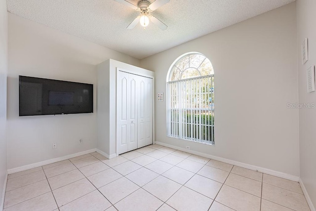 unfurnished bedroom with light tile patterned floors, baseboards, a closet, and a textured ceiling